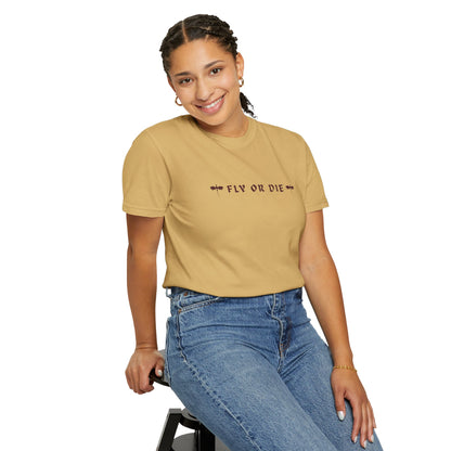 Person wearing a beige t-shirt with 'FLY OR DIE' text and blue jeans on a white background