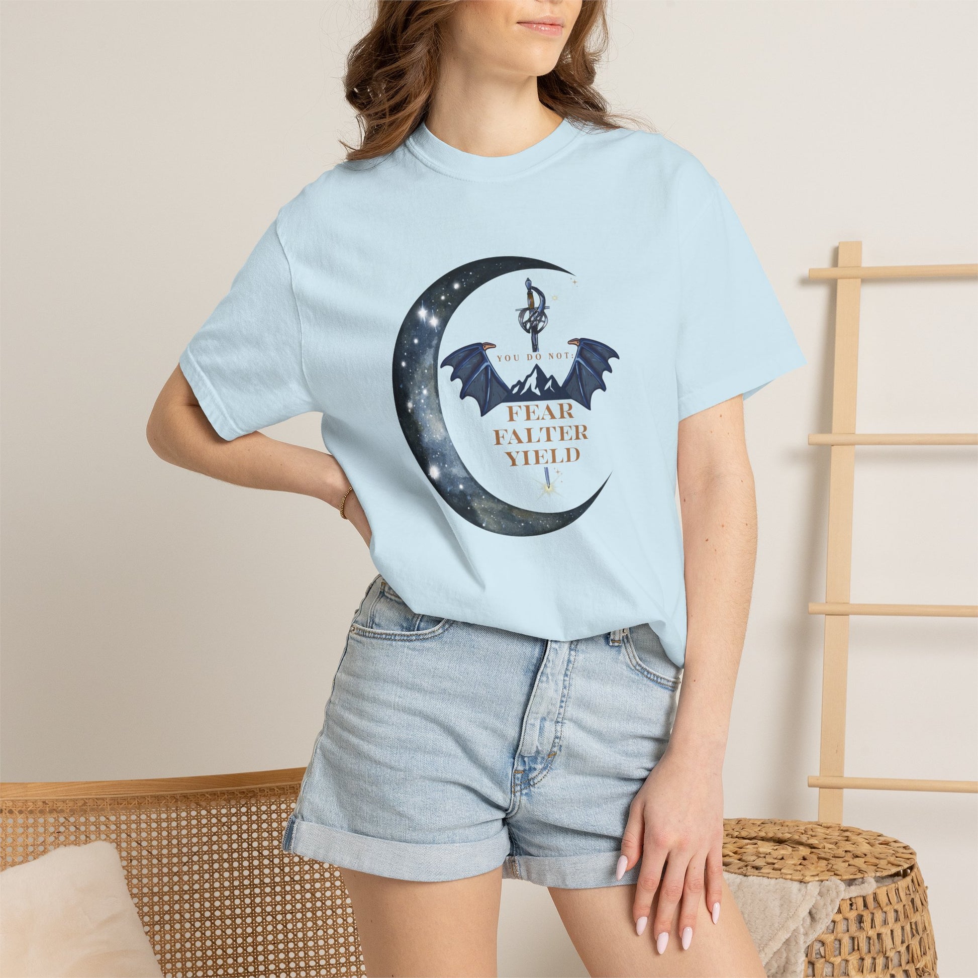 Person wearing a light blue t-shirt with a graphic design and text, standing against a neutral background.