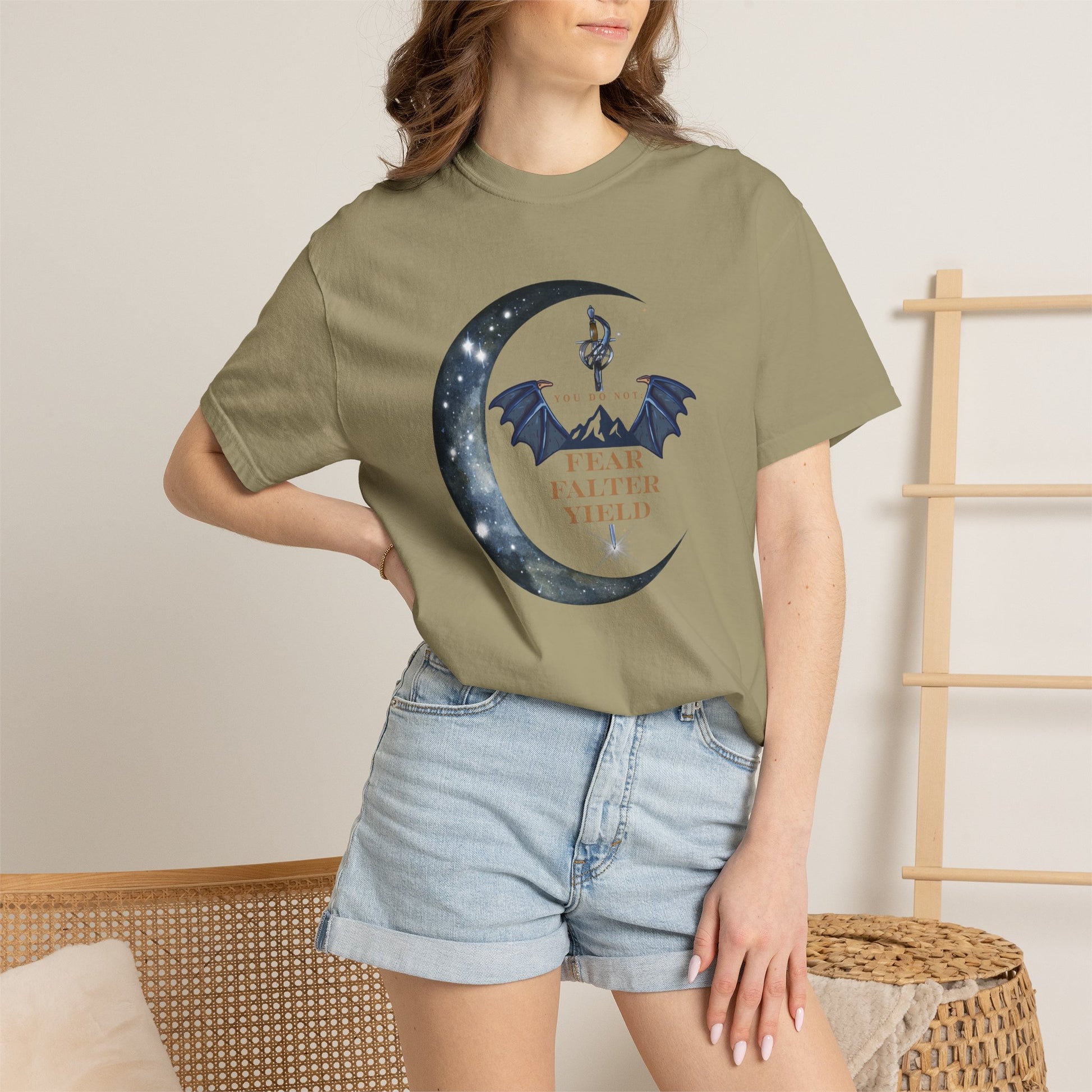 Person wearing a green t-shirt with a graphic design of a crescent moon and dragon, standing against a neutral background.
