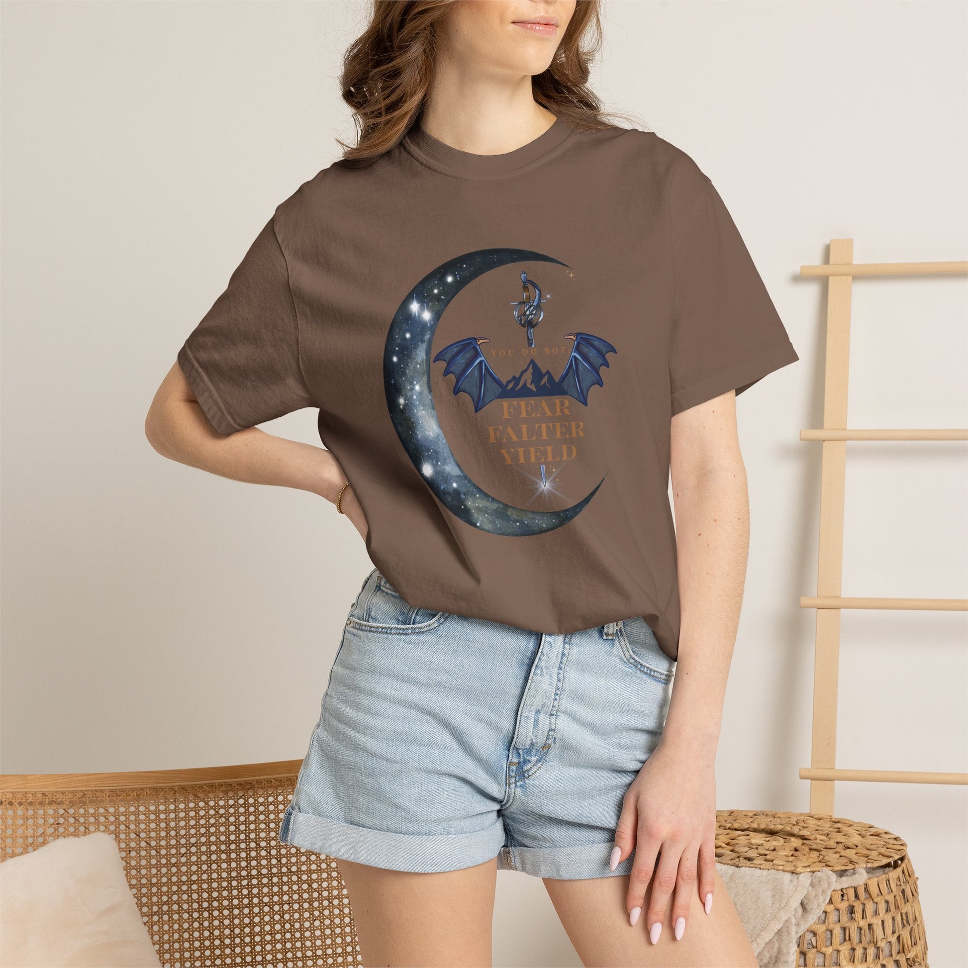 Person wearing a brown t-shirt with a graphic design and text, standing against a neutral background.
