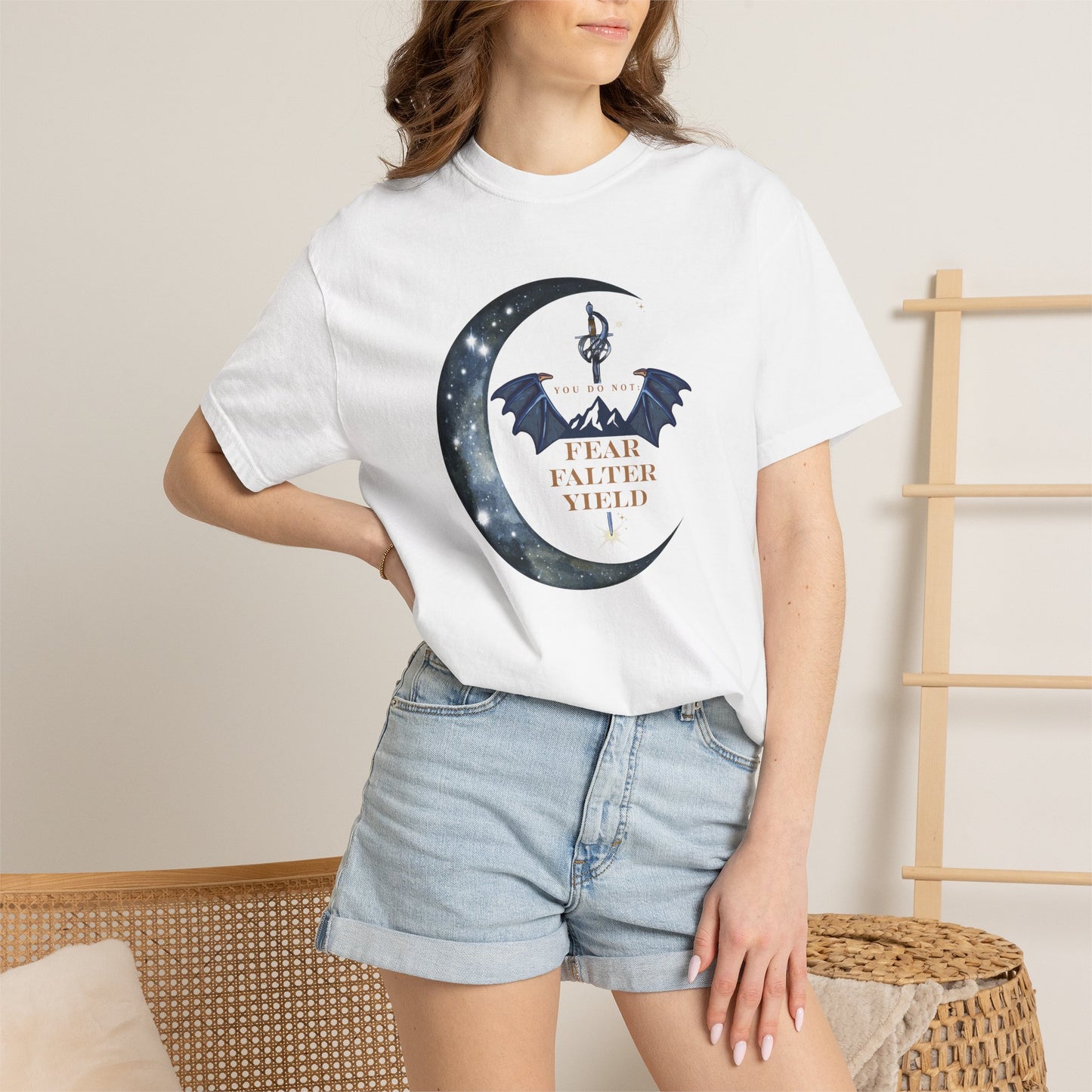 Person wearing a white t-shirt with a graphic design and denim shorts in a casual setting.